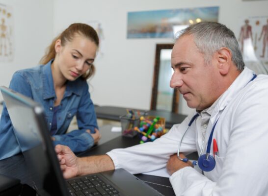 Médecin avec une patiente sur un ordinateur.
