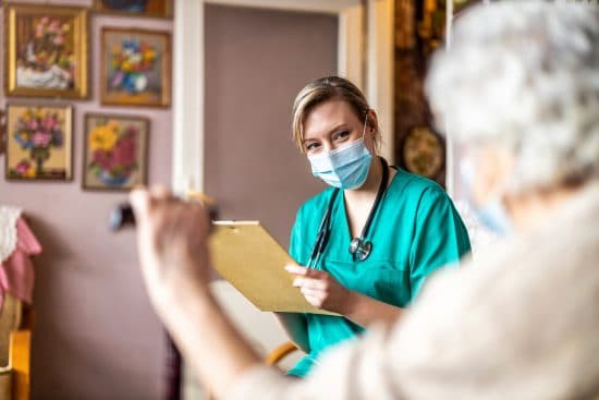 Infirmière qui prend des notes avec une patiente.